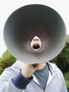 Unique brand voice: image of a young man yelling through a megaphone

