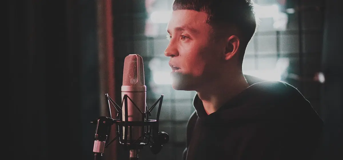 How much does voice over narration cost? Young man standing in front of microphone
